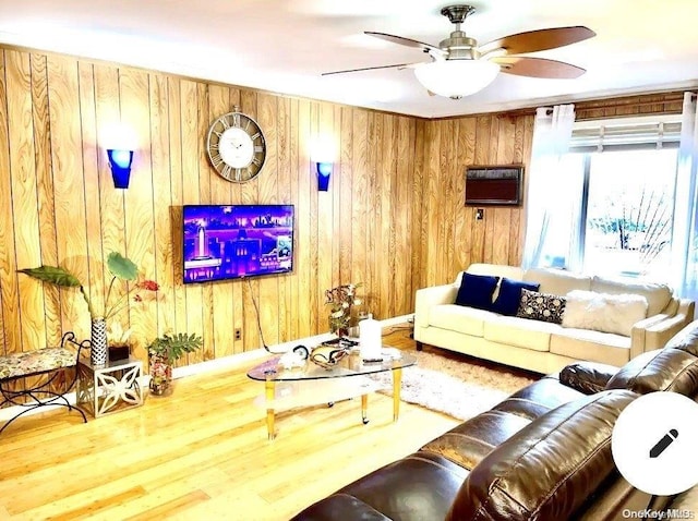 living room with wood-type flooring, ceiling fan, and wood walls