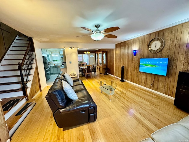 living room featuring ceiling fan, wood walls, light wood-type flooring, and crown molding