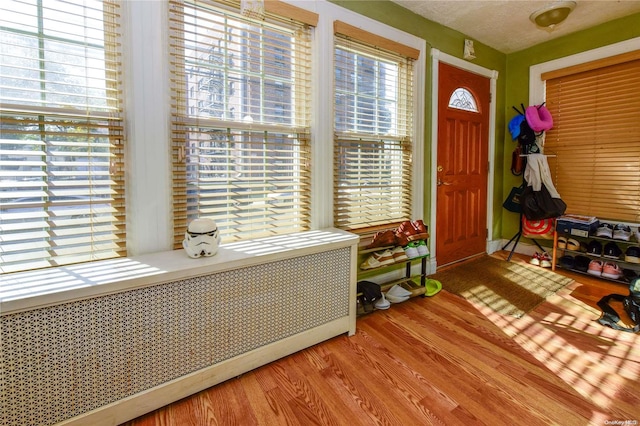 entrance foyer with radiator, wood-type flooring, and a textured ceiling