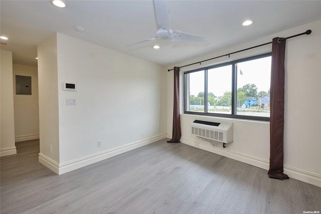 unfurnished room with a wall mounted air conditioner, light wood-type flooring, electric panel, and ceiling fan