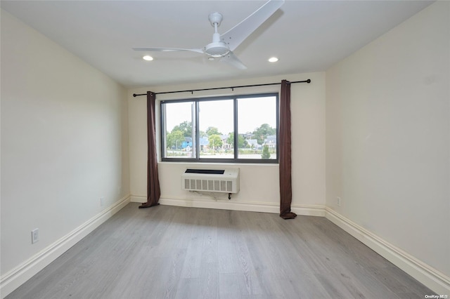 spare room with ceiling fan, light wood-type flooring, a wall unit AC, and heating unit