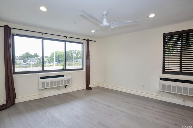 unfurnished room featuring hardwood / wood-style floors, heating unit, and ceiling fan