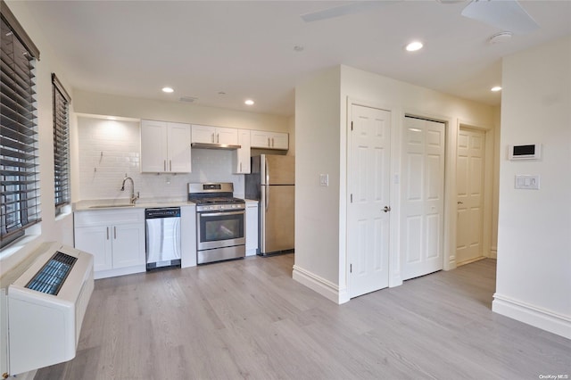 kitchen with backsplash, white cabinets, sink, light hardwood / wood-style floors, and stainless steel appliances