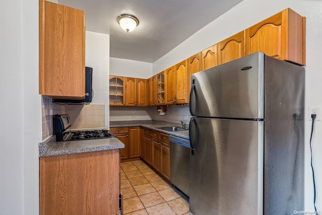 kitchen with tasteful backsplash, sink, light tile patterned flooring, and stainless steel appliances