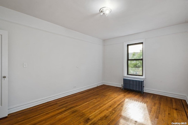 unfurnished room with hardwood / wood-style floors and radiator heating unit