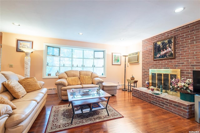 living room featuring hardwood / wood-style floors, a wall mounted air conditioner, baseboard heating, and a brick fireplace