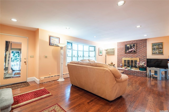 living room with a brick fireplace, baseboard heating, dark wood-type flooring, and a wall unit AC