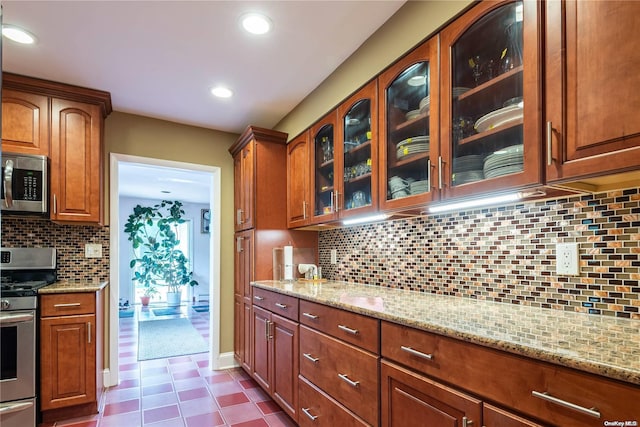 kitchen featuring backsplash, light stone countertops, and appliances with stainless steel finishes