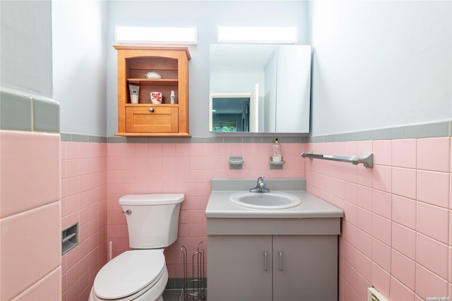 bathroom with vanity, toilet, and tile walls