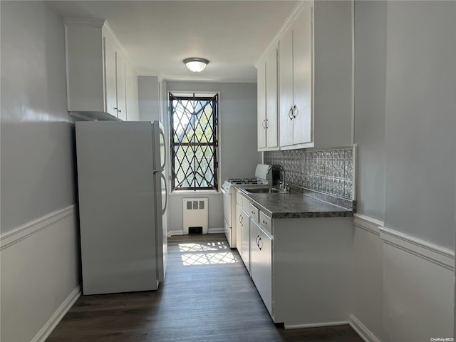 kitchen with tasteful backsplash, white appliances, white cabinets, radiator heating unit, and dark hardwood / wood-style floors