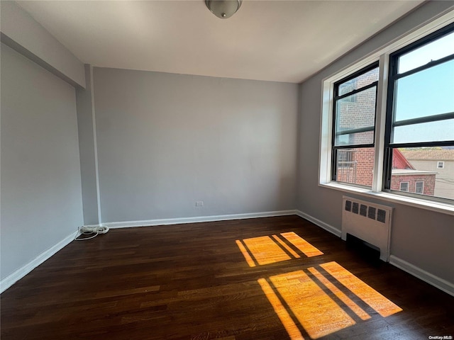 spare room with dark hardwood / wood-style flooring and radiator heating unit