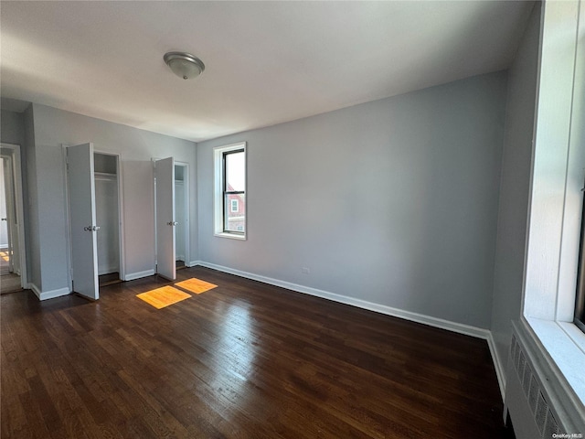 unfurnished bedroom featuring dark hardwood / wood-style flooring and radiator heating unit