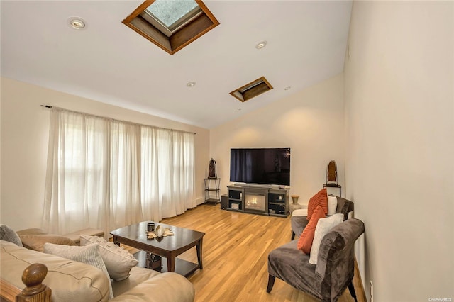 living room featuring light wood-type flooring and vaulted ceiling with skylight