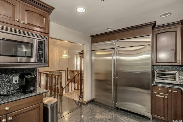 kitchen with pendant lighting, built in appliances, and tasteful backsplash