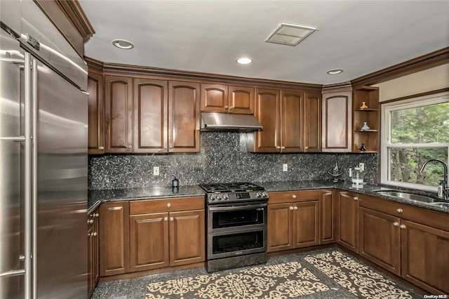 kitchen with dark stone countertops, sink, stainless steel appliances, and tasteful backsplash