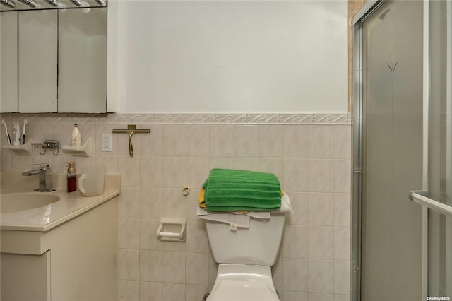 bathroom featuring a shower with door, vanity, tile walls, and toilet