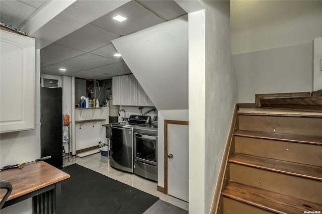 kitchen with a paneled ceiling, white cabinetry, and independent washer and dryer