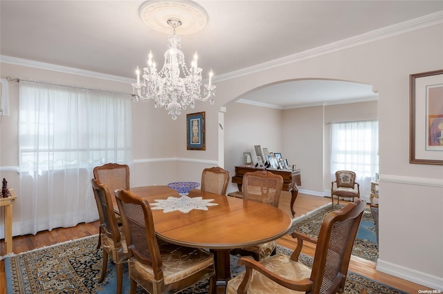 dining area with wood-type flooring, crown molding, and a chandelier