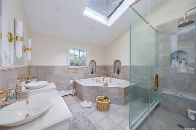 bathroom featuring tile patterned floors, shower with separate bathtub, vaulted ceiling with skylight, vanity, and tile walls