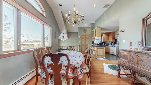 dining space featuring a baseboard heating unit, light hardwood / wood-style flooring, and a chandelier