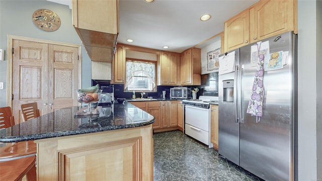 kitchen featuring sink, appliances with stainless steel finishes, light brown cabinetry, decorative backsplash, and dark stone counters