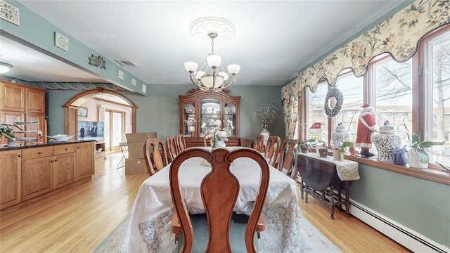 dining area featuring a baseboard heating unit, a notable chandelier, a wealth of natural light, and light hardwood / wood-style floors