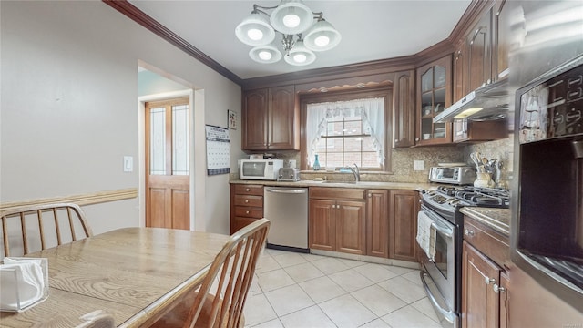 kitchen with light tile patterned flooring, tasteful backsplash, ornamental molding, stainless steel appliances, and an inviting chandelier