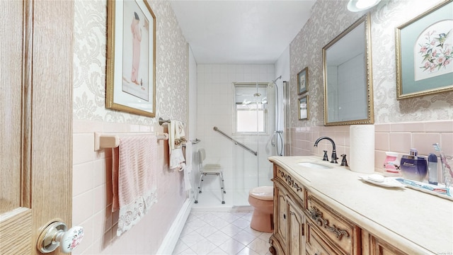 bathroom featuring a shower with shower door, tile walls, vanity, toilet, and tile patterned floors