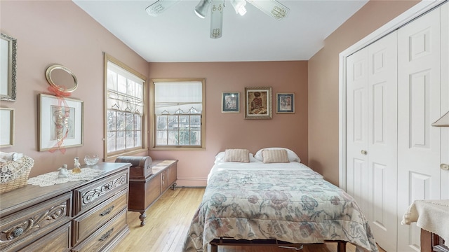 bedroom featuring ceiling fan, a baseboard radiator, light hardwood / wood-style floors, and a closet