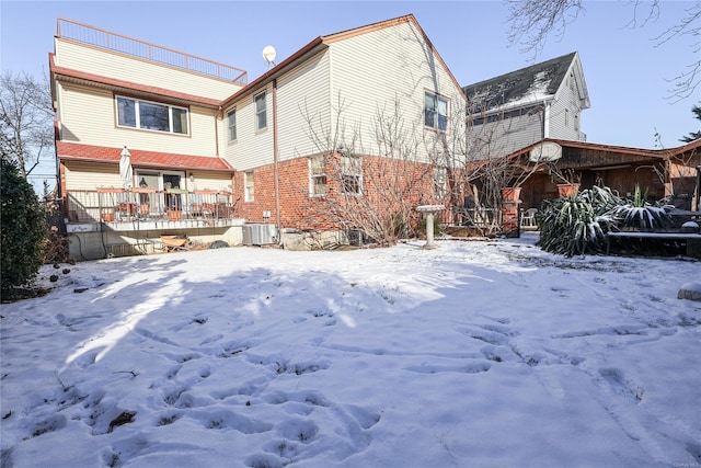 snow covered back of property featuring central AC unit