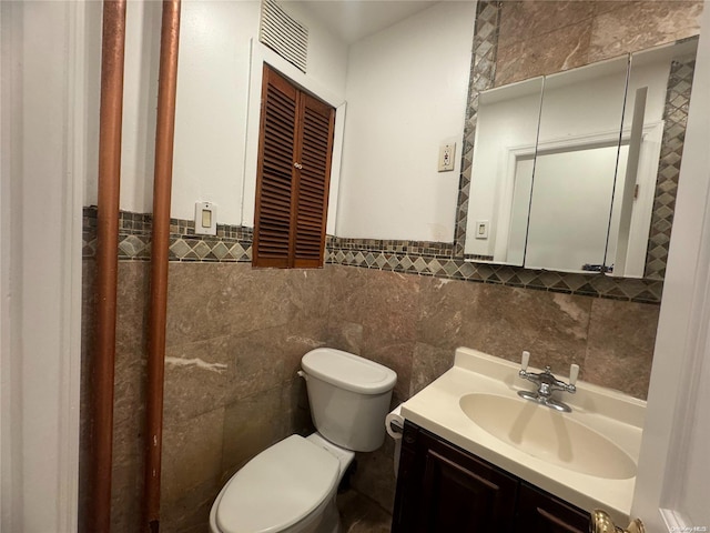 bathroom featuring vanity, toilet, and tile walls