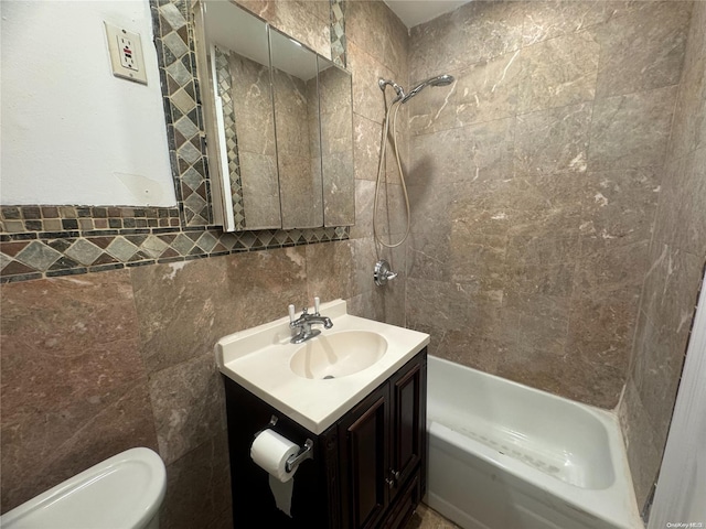 full bathroom featuring tiled shower / bath, vanity, toilet, and tile walls