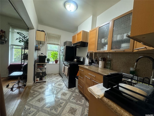 kitchen featuring tasteful backsplash, stainless steel range with gas cooktop, sink, and light hardwood / wood-style flooring