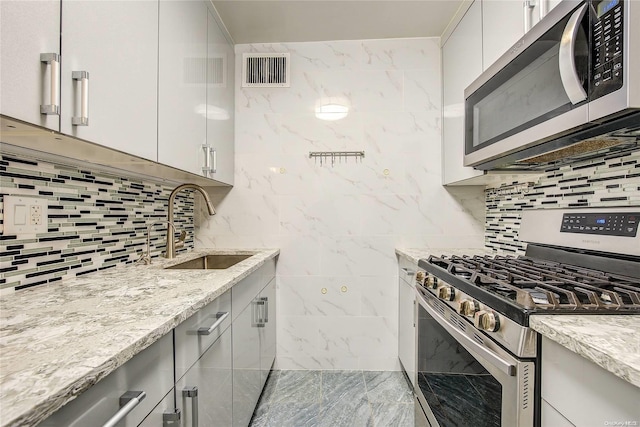 kitchen featuring light stone countertops, appliances with stainless steel finishes, backsplash, and sink