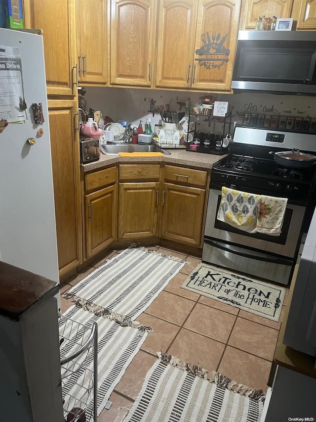 kitchen with light tile patterned flooring, sink, and appliances with stainless steel finishes