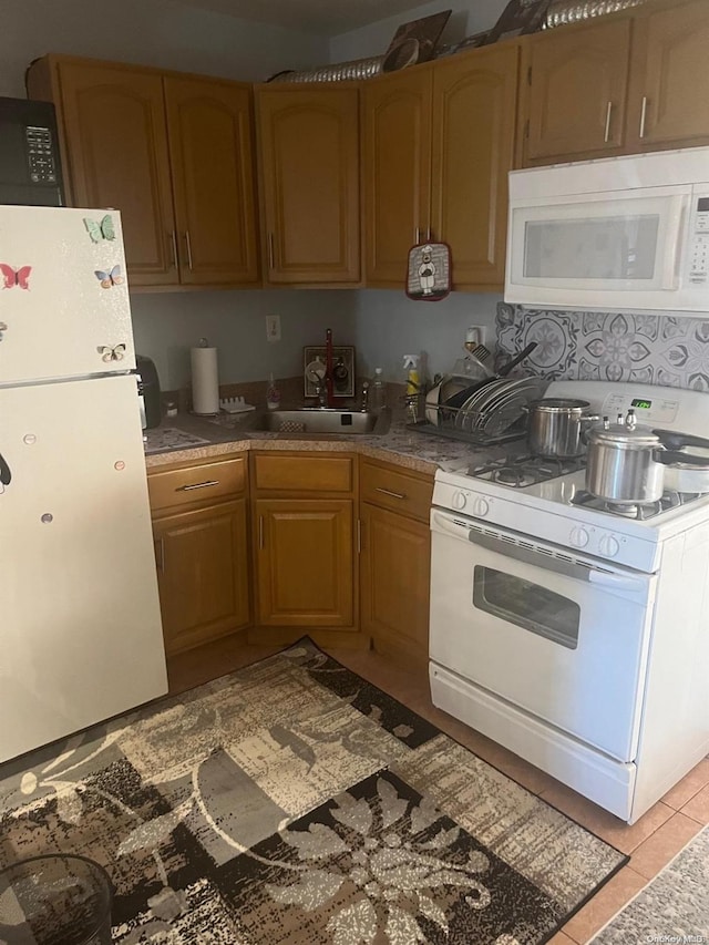 kitchen featuring light tile patterned floors, white appliances, and sink