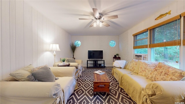 living room featuring ceiling fan, brick wall, and wood walls