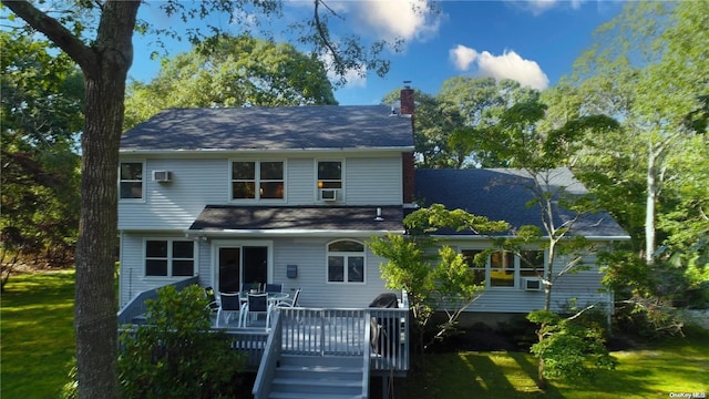 back of property featuring a lawn, a wall mounted air conditioner, and a deck