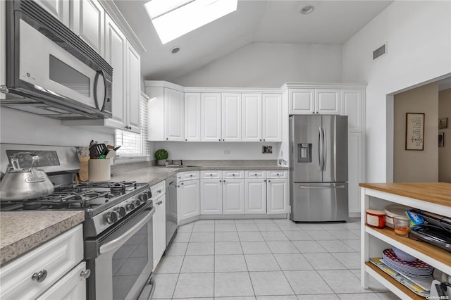 kitchen with white cabinets, appliances with stainless steel finishes, a skylight, and light tile patterned floors