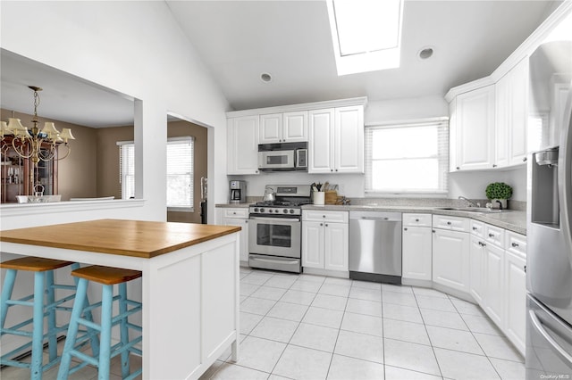 kitchen with lofted ceiling with skylight, white cabinets, and appliances with stainless steel finishes