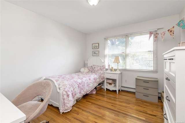 bedroom featuring light wood-type flooring and a baseboard heating unit