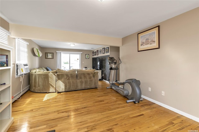 living room with cooling unit, light hardwood / wood-style floors, and a baseboard heating unit