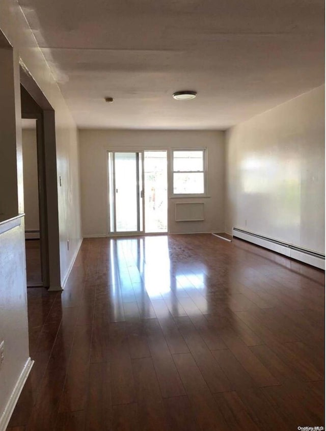 empty room with baseboard heating and dark wood-type flooring