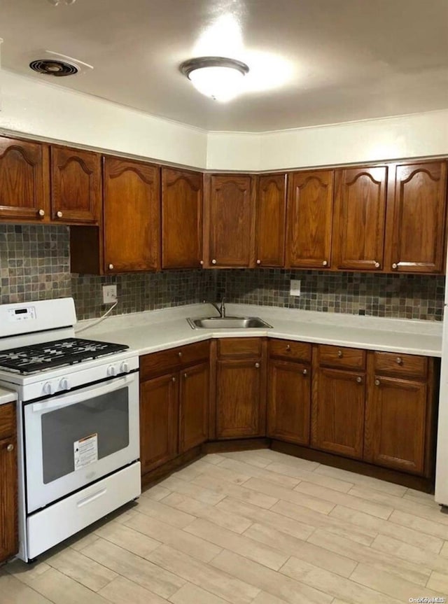 kitchen featuring tasteful backsplash, sink, light hardwood / wood-style flooring, and white gas range oven