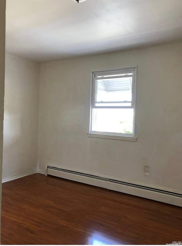 spare room with dark hardwood / wood-style floors and a baseboard radiator