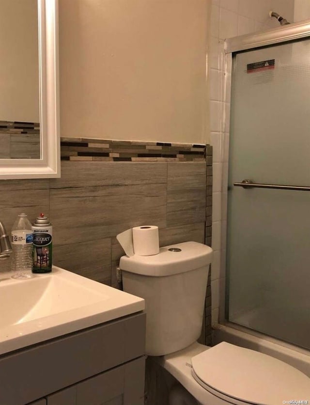 bathroom with vanity, toilet, and tile walls