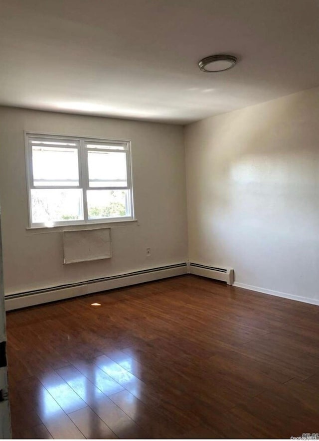 spare room featuring a baseboard radiator and dark hardwood / wood-style floors