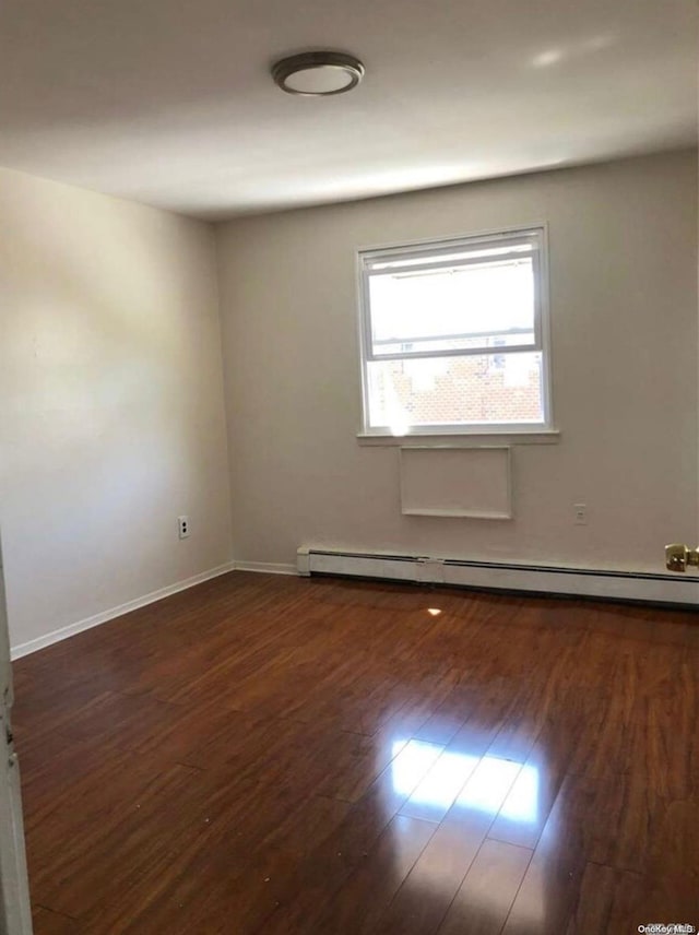 unfurnished room featuring baseboard heating and dark wood-type flooring