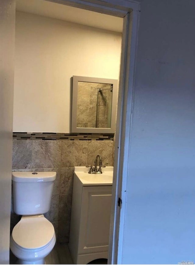 bathroom featuring vanity, toilet, and tile walls