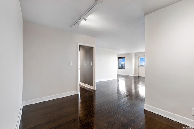 unfurnished room with rail lighting and dark hardwood / wood-style floors